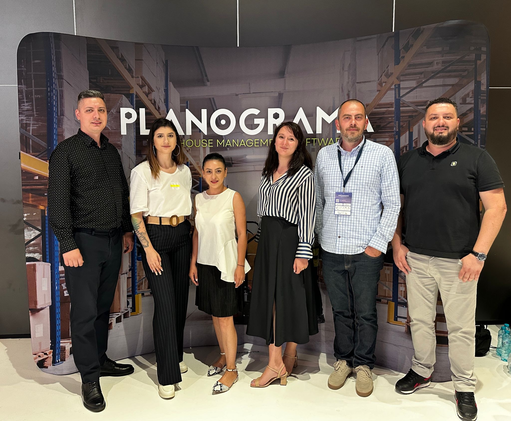 Six people posing in front of the Planograma stand's backdrop at dotCommerce