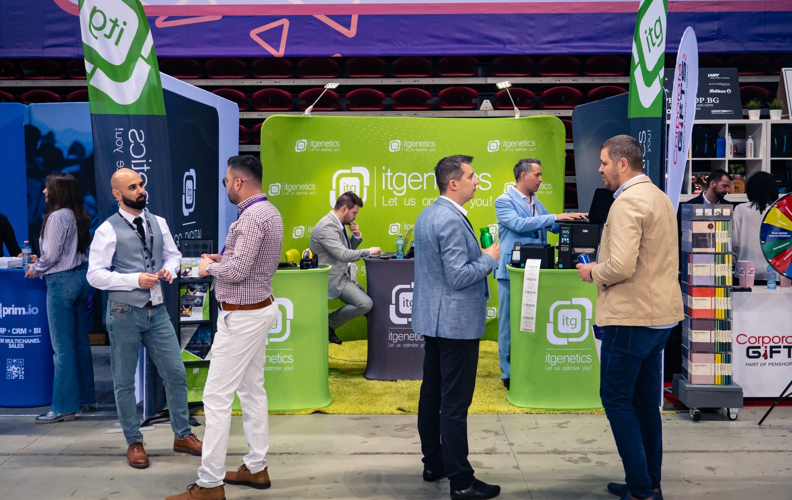 Visitors in conversation with staff at the IT Genetics stand, with label printers on the counter printing barcode labels
